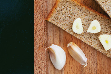 Pieces of black bread and garlic on a cutting board