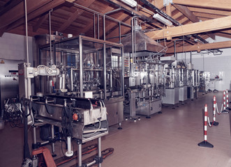 Naklejka na ściany i meble Wine bottling equipment line in a hangar, toned