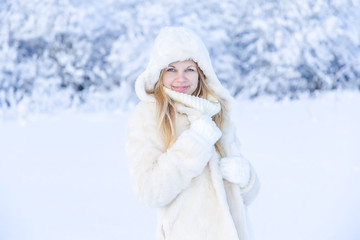 Portrait close up of young beautiful woman in white fur coat on winter park nature background