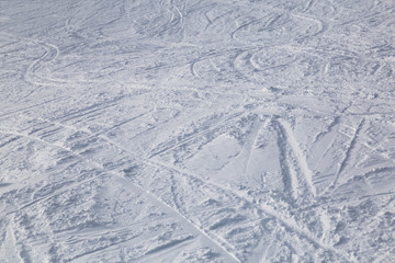 Traces from skiing on white snow .