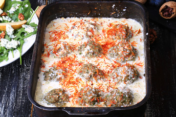 raw meatballs in a creamy sauce with saffron dark rural background