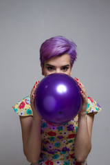 Violet short-haired woman holding a balloon with her two hands