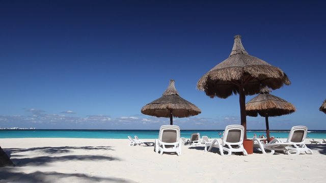 Beach chairs and grass umbrellas on a stunning tourist resort beach
