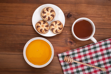Cup of tea biscuits and honey on wooden background.