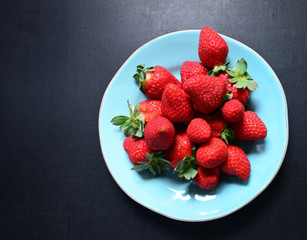 Strawberries on plate on black background