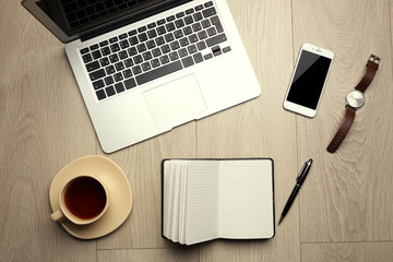 Office set with laptop, mobile phone, notebook, coffee cup, watch and pen on wooden table