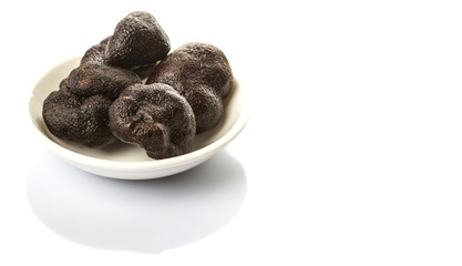 Black truffle mushroom in white bowl over white background