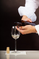 Man waiter pouring white wine into glass.