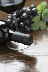 Abstract Wine Bottle, Glass and Grapes on Reflective Wood Surface.