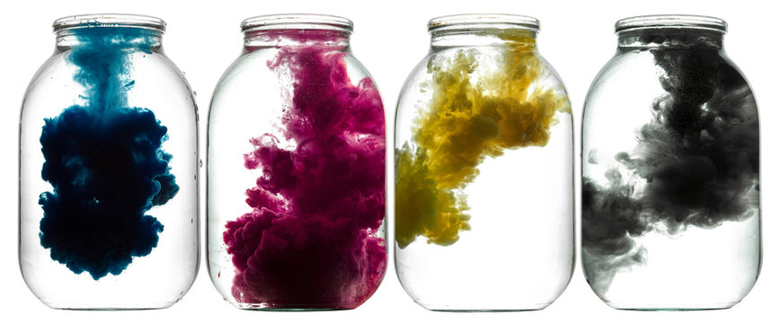 CMYK paint swirling in water. Splashes of paint in a glass jar. 