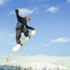 Naklejka na ściany i meble Snowboarder doing high jump above the mountain