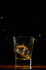 Fototapeta na wymiar Whiskey splash in glass on black