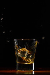 Whiskey splash in glass on black