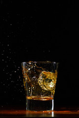Whiskey splash in glass on black