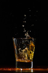 Whiskey splash in glass on black
