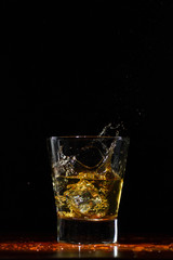 Whiskey splash in glass on black