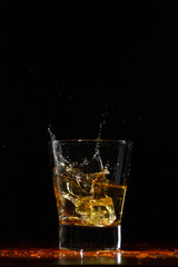 Whiskey splash in glass on black
