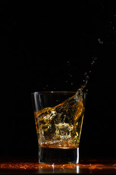 Whiskey splash in glass on black