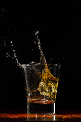 Whiskey splash in glass on black