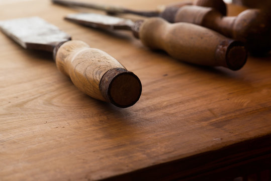 Old and well used wood carving chisels, on a old workbench. Old chisel with an oak handle. Shallow depth of field.