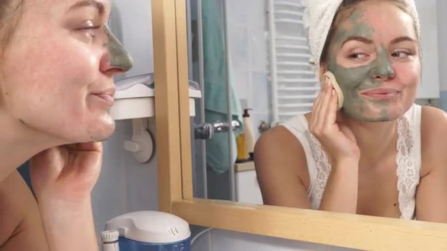 Woman removing facial clay mud mask in bathroom 4K