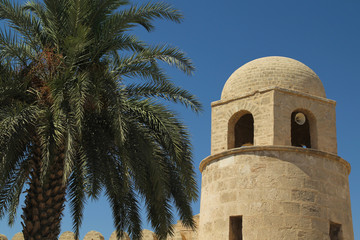 Fototapeta na wymiar Islamic mosque tower with a palm in foreground