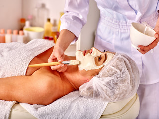 Woman middle-aged look up take facial and neck clay mask in spa salon. Two female people.