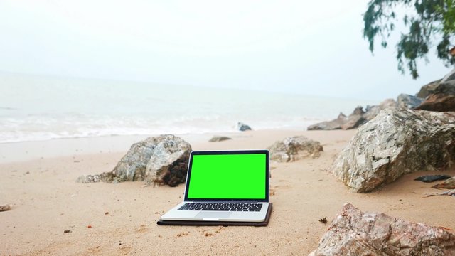 laptop on the beach, keylight green background.