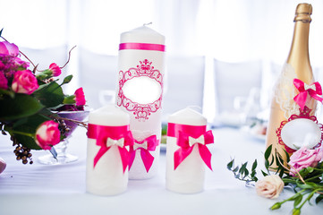 Wedding candles with pink ribbons and golden bottle of champagne
