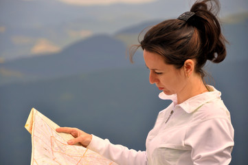 Girl tourist in mountain read the map.