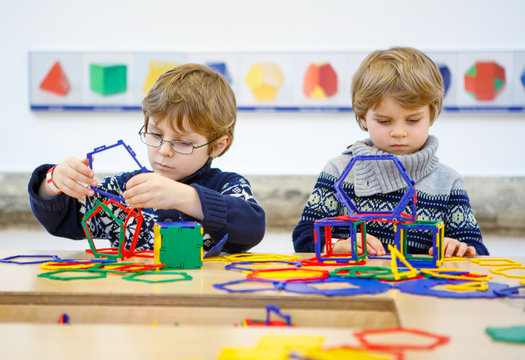Two little kid boys building geometric figures 