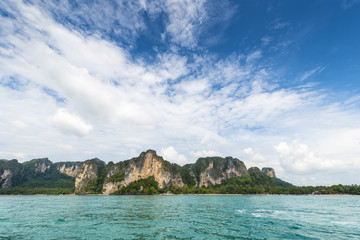 Thailand tropical island cliffs over ocean water during tourist boat trip in Railay Beach resort