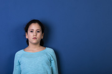 junges Mädchen steht mit dem Rücken an einer blauen Wand