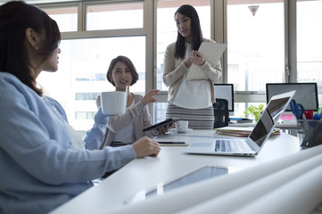 Three women are talking in the office