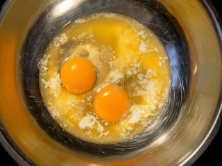 Hot butter and two eggs in steel scratched bowl