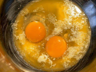 Hot butter and two eggs in steel scratched bowl