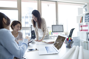 Naklejka premium Three women have been meeting while looking at the tablet in the office