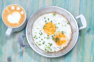 Hot late art coffee and Egg in pan on wood table