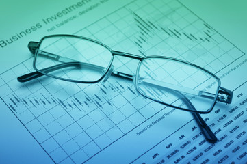 Glasses on stock market graph, financial concept