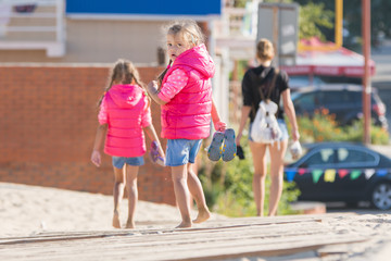 Mother and two daughters are on the wooden flooring in the sand, one girl turned