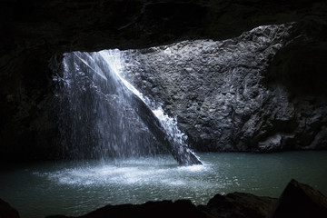 Gruta con cascada y salida al bosque iluminada con luz natural. Australia