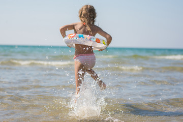 Girl runs to bathe in the sea, focus on a spray of water