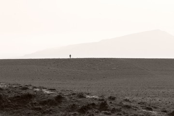 Fototapeta na wymiar Distant man standing on plateau on hills in Azerbaijan. A sense of scale and smallness in hills not far from Baku, capital of Azerbaijan 