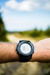 Runner on mountain trail looking at stopwatch, activity tracker