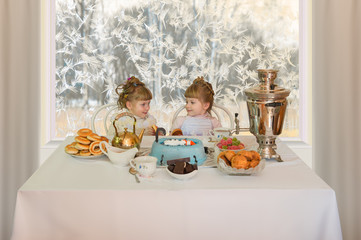 Cup of tea/Sisters twins for a Cup of tea on the background of a window