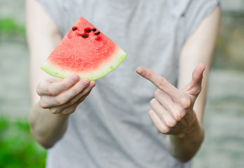 Summer and fresh watermelon theme: a man holds a slice of watermelon on a green background