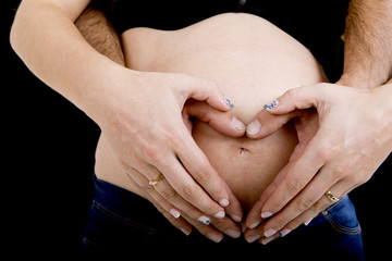 Couple hands making a heart over her belly