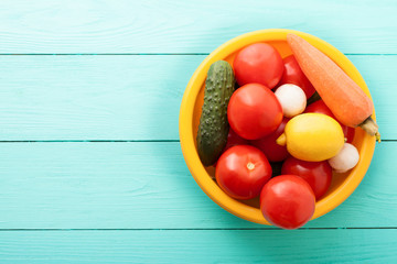 Fresh vegetables in plate on blue wooden kitchen. Top view and copy space
