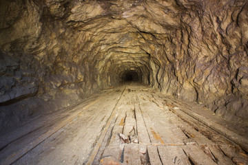 Old abandoned iron mine tunnel passage with rails, wood boards