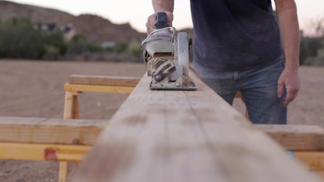 A carpenter sawing a board
